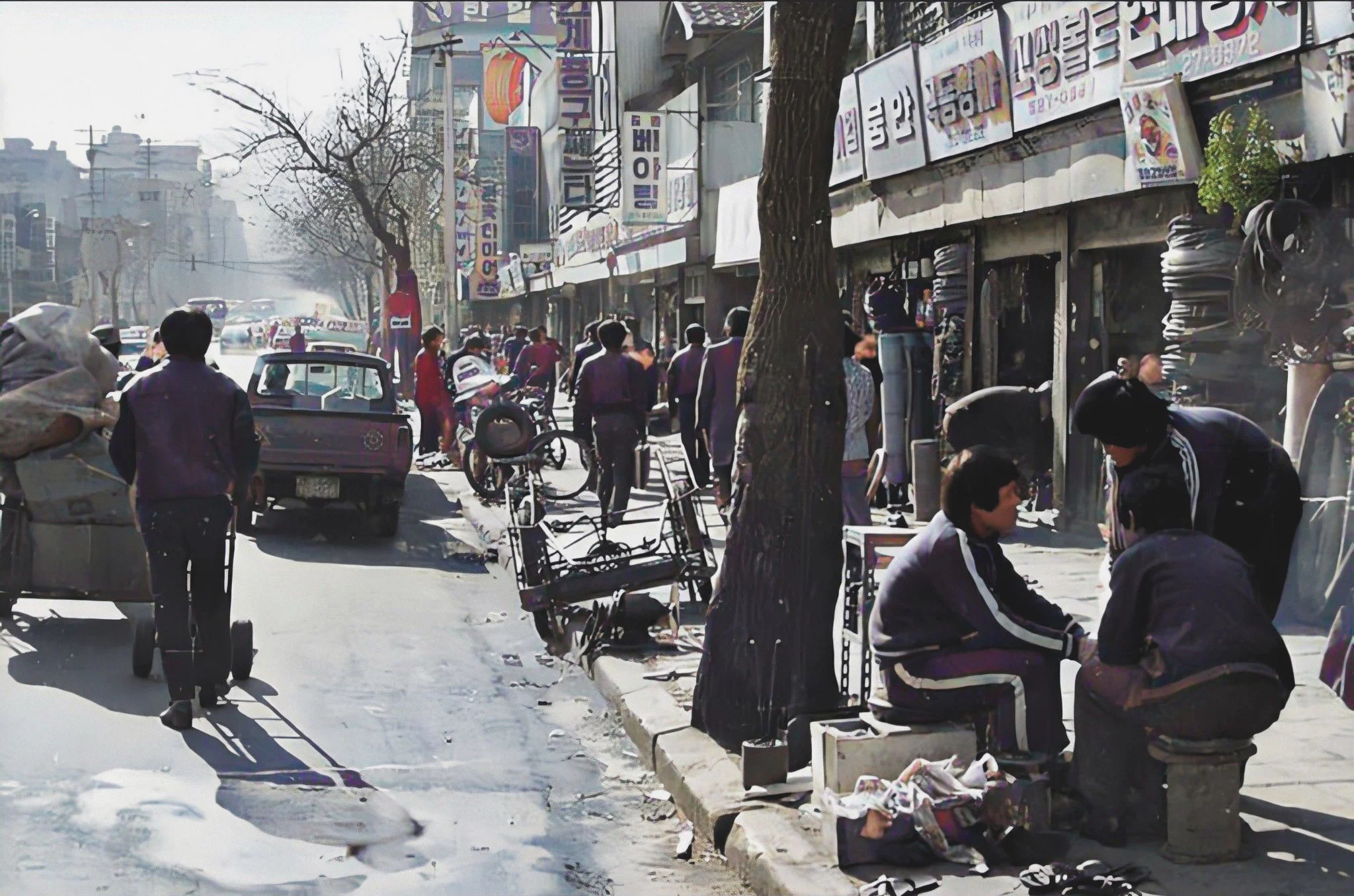 가로수의 상태로 보아 겨울로 추정되며, 구두닦이로 보이는 사람들이 모여 앉아 이야기를 나누며 불을 쬐고 있다. 뒤에는 갈아 끼울 연탄에 연탄집게가 꽂혀 대기하고 있다. 1