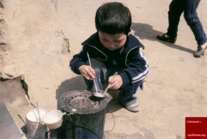 1970년대, 달고나 상인이 가져온 연탄불 위에서 국자에 설탕을 넣고 녹이고 있는 아이의 모습. 7