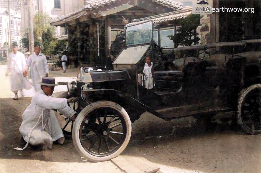 1925년, 경성의 거리에서 한 남성이 포드자동차의 시동을 걸고 있다. 초기의 자동차 엔진은 사진과 같이 수동키를 꽂은 다음 손으로 돌려 시동을 걸었다. 1