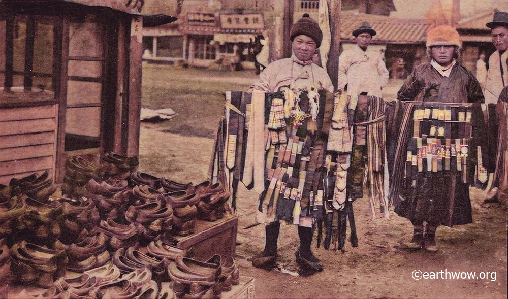 1920년대, 경성의 거리에서 댕기와 머리띠를 들고 판매하는 상인들의 모습. 왼쪽의 상점 앞 매대에 '호모화(護謨靴)'라고도 불렸던 고무신이 가득 쌓여있다. 1