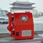 사진 속 공중전화기의 정식 명칭은 '체신 701-A형 공중전화기'로 1977년에 공중전화 요금이 도수당 10원으로 인상되면서 10원 동전에 대응할 수 있도록 기존의 '체신 1호 벽괘형 공중전화기'를 개조하여 1978년부터 설치되었다. 즉 사진이 찍힐 당시에는 최신형 제품으로 놓였다. 7