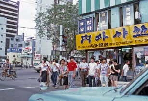 시민들이 서 있는 뒤편으로 '내외(內外)샤쓰' 종로2가 영업부의 노란색 간판이 보인다. 내외샤쓰는 1970년대 중반까지 세계 15개국에 수출하고 전국 300개 이상의 체인점을 두며 인기를 끌었고, 사진이 촬영된 1년 후인 1976년 6월에 부산제복(釜山制服)과 합병하며 사세를 키웠다. 9